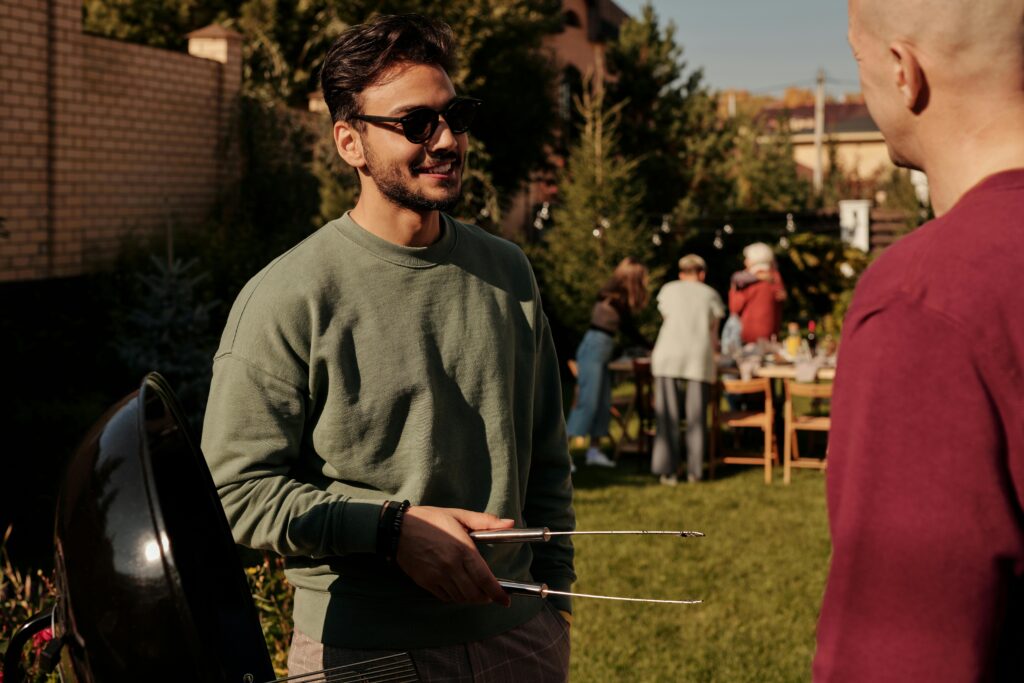 A relaxed backyard barbecue featuring friends enjoying conversation and grilling outdoors.